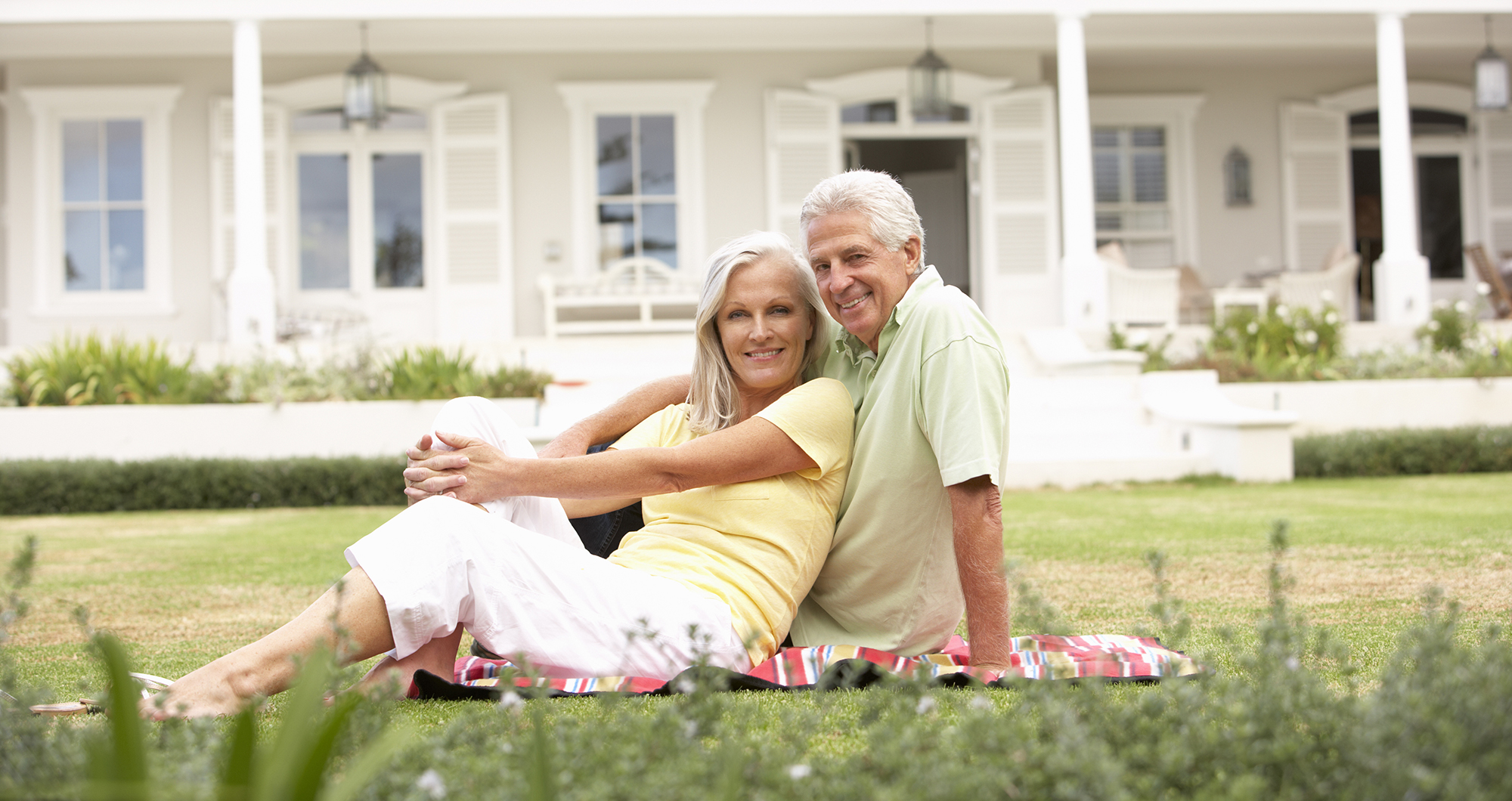 Grandparents And Grandchildren Sitting Outside House On Lawn Mature couple living in a retirement community.